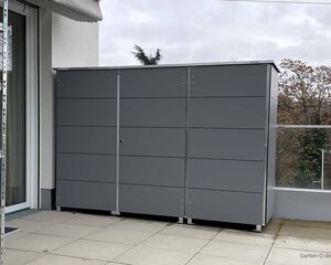 Grauer Gartenschrank auf einer Terrasse, daneben eine Leiter.