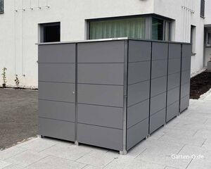 Ein graues Gartenschrank-System steht neben einem modernen Gebäude auf einem gepflasterten Hof.